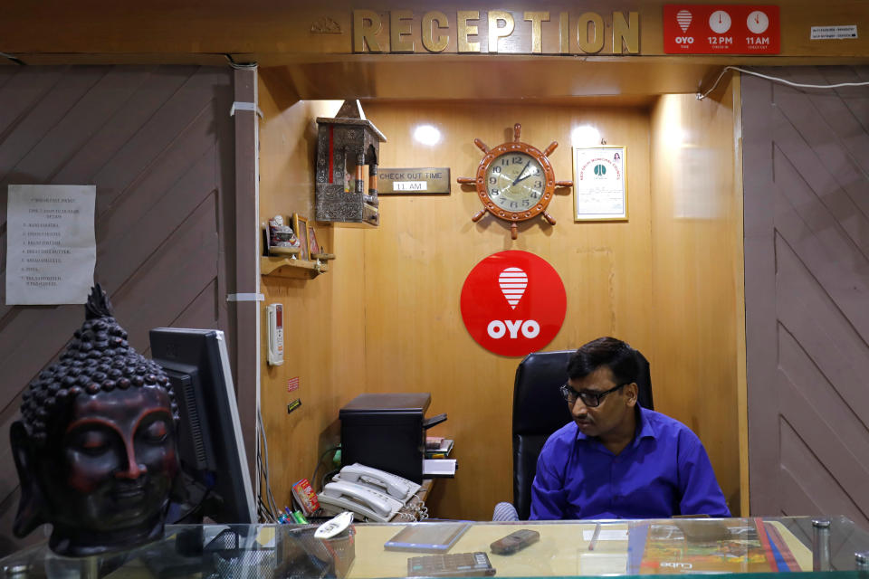 An employee sits next to the logo of OYO, India's largest and fastest-growing hotel chain, at the reception of a hotel in New Delhi, India, September 25, 2018. REUTERS/Anushree Fadnavis