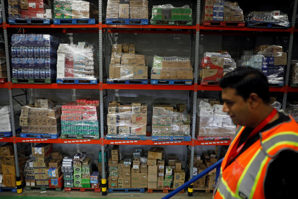 An employee passes goods on shelves at RedMart's fulfillment centre in Singapore September 22, 2017. Picture taken September 22, 2017. REUTERS/Edgar Su