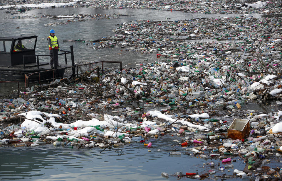 A boat pushes tons of garbage stuck at the foot of the hydro power plant at the Potpecko accumulation lake near Priboj, in southwest Serbia, Friday, Jan. 22, 2021. Serbia and other Balkan nations are virtually drowning in communal waste after decades of neglect and lack of efficient waste-management policies in the countries aspiring to join the European Union. (AP Photo/Darko Vojinovic)