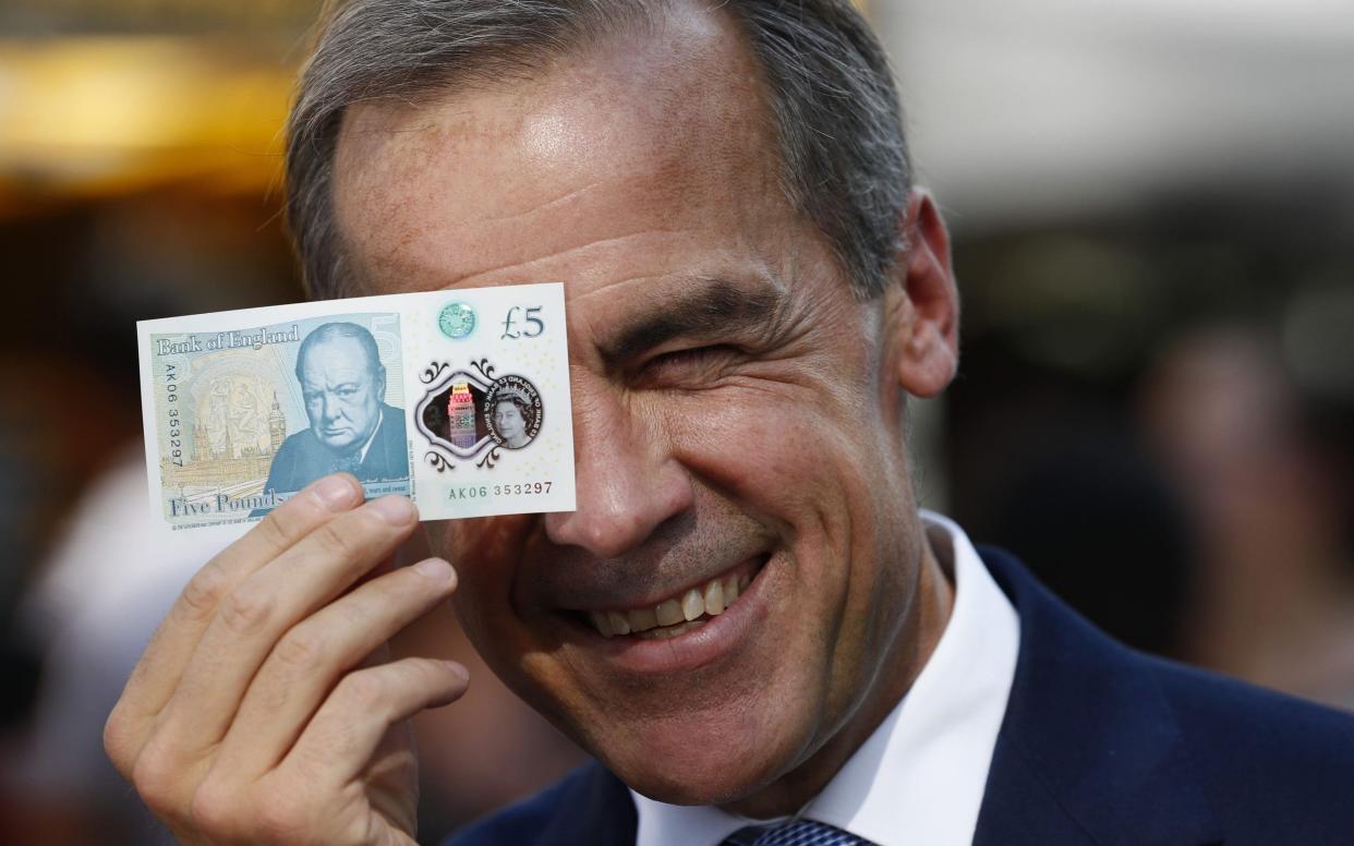 Bank of England Governor Mark Carney holding a new plastic £5 note - PA Wire