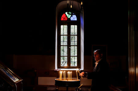 A man lights a candle inside a church at the Asomaton-Petraki monastery in Athens, Greece, February 7, 2017. REUTERS/Alkis Konstantinidis