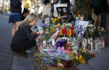 A woman lights a candle at a makeshift shrine for 20-year-old UCSB student Christopher Michael-Martinez outside a deli that was one of nine crime scenes after series of drive-by shootings that left 7 people dead in the Isla Vista neighborhood of Santa Barbara, California May 26, 2014. REUTERS/Lucy Nicholson