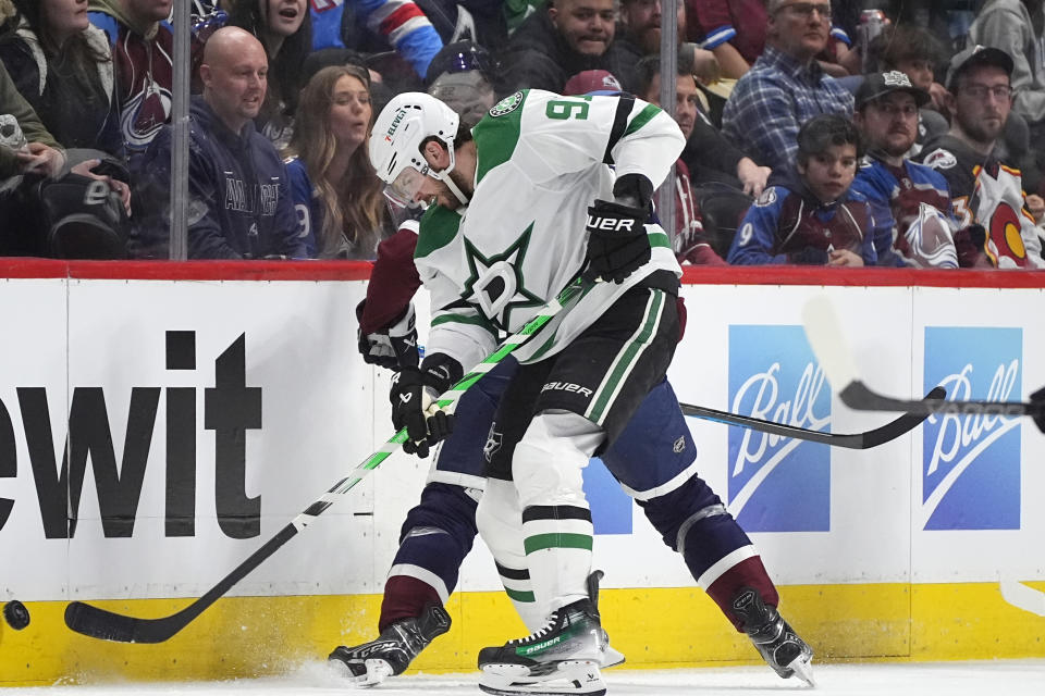 Dallas Stars center Tyler Seguin, front, clears the puck while checking Colorado Avalanche left wing Zach Parise in the second period of an NHL hockey game Sunday, April 7, 2024, in Denver. (AP Photo/David Zalubowski)