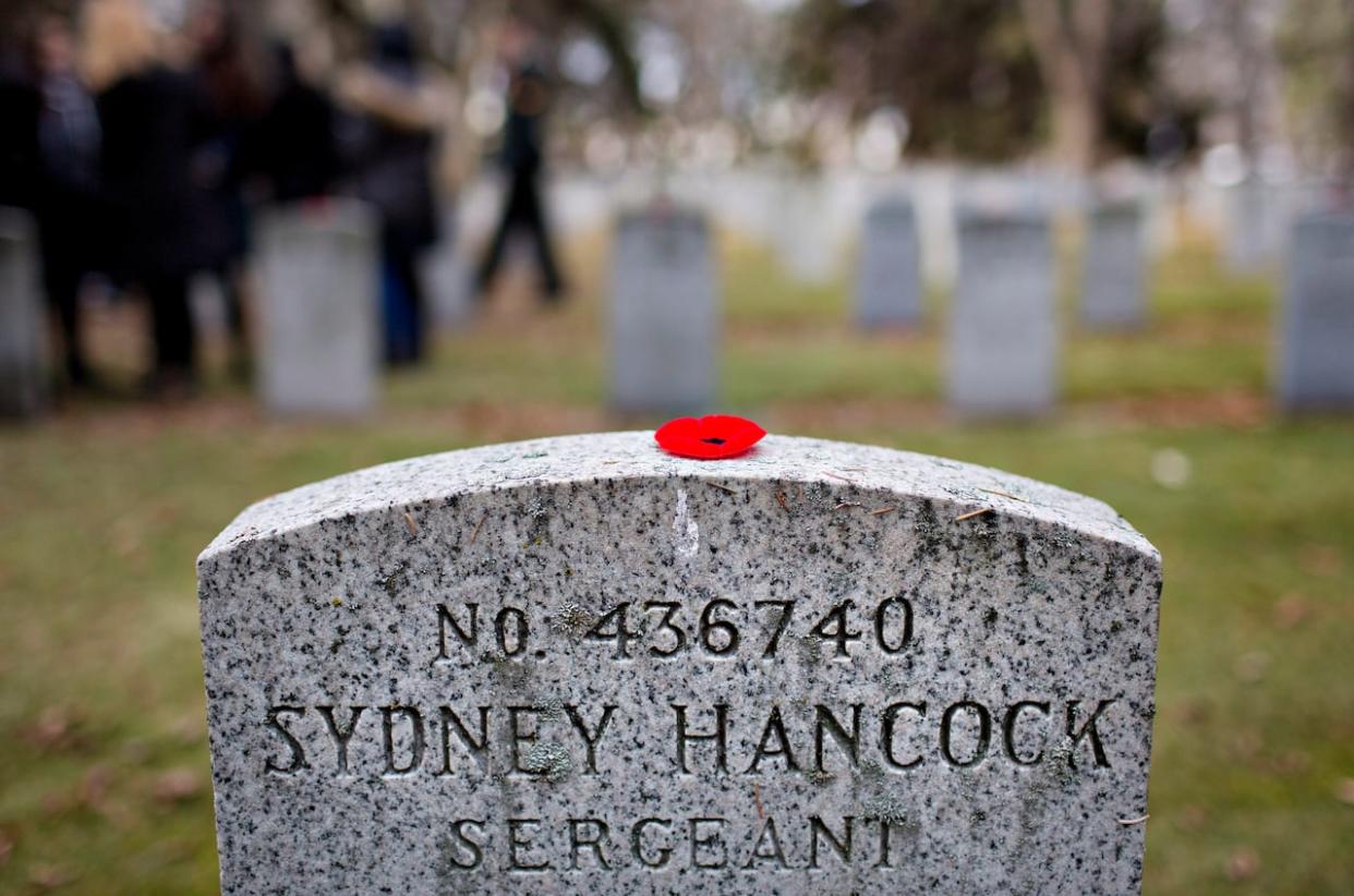 A poppy lies on a grave during a commemoration event at Beechmount Cemetery in Edmonton. (Jason Franson/Canadian Press - image credit)