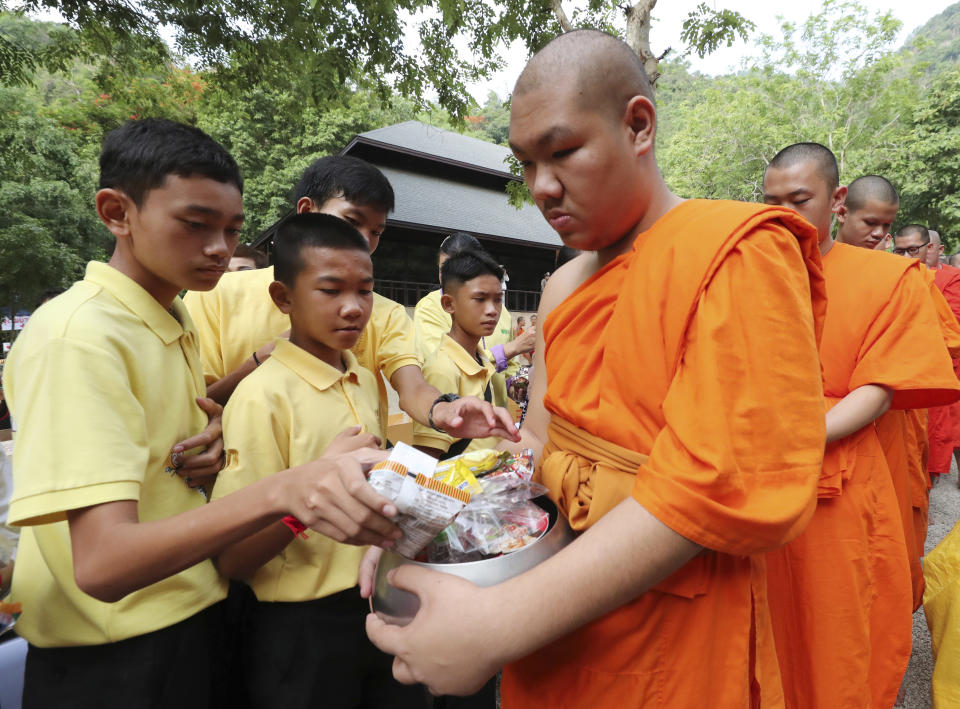 Members of the Wild Boars soccer team who were rescued from a flooded cave, offer foods to Buddhist monks near the Tham Luang cave in Mae Sai, Chiang Rai province, Thailand Monday, June 24, 2019. The 12 boys and their coach attended a Buddhist merit-making ceremony at the Tham Luang to commemorate the one-year anniversary of their ordeal that saw them trapped in a flooded cave for more than two weeks. (AP Photo/Sakchai Lalit)