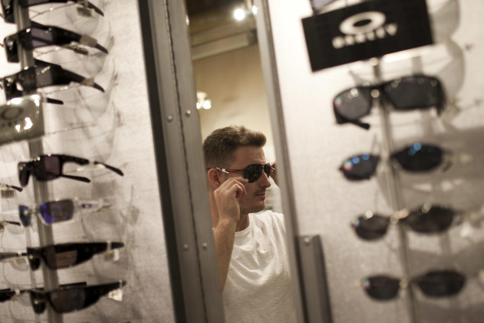 In this March 4, 2012 photo, Leonardo Queiroz, from Brasilia, Brazil, tries on sun glasses as he shops in Miami, Florida. Brazilian travelers spend more per capita than any other visitors to the U.S. (AP Photo/Felipe Dana)