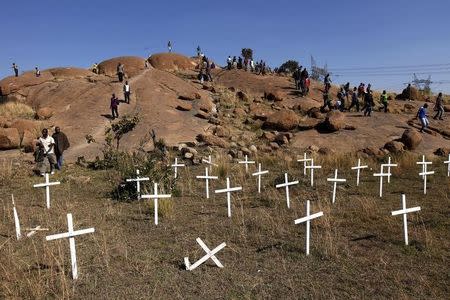 Members of the mining community walk near crosses placed at a hill known as the "Hill of Horror", where 43 miners died during clashes with police last year, during a strike at Lonmin's Marikana platinum mine in Rustenburg, 100 km (62 miles) northwest of Johannesburg, May 14, 2013. . REUTERS/Siphiwe Sibeko