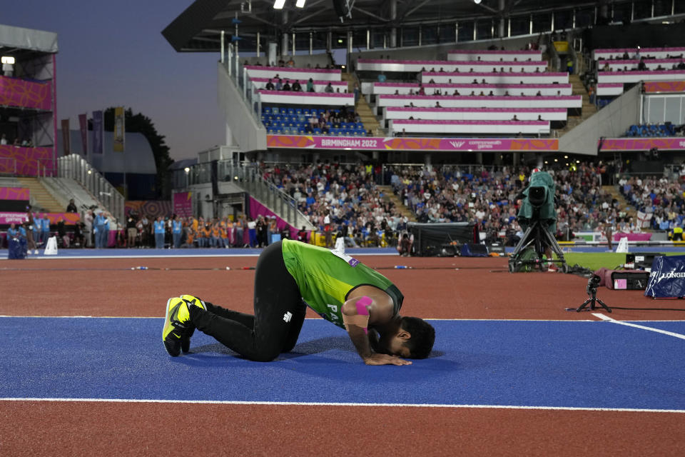 Arshad Nadeem of Pakistan touches his forehead to the track after winning the gold medal in the Men's javelin throw during the athletics competition in the Alexander Stadium at the Commonwealth Games in Birmingham, England, Sunday, Aug. 7, 2022. (AP Photo/Alastair Grant)