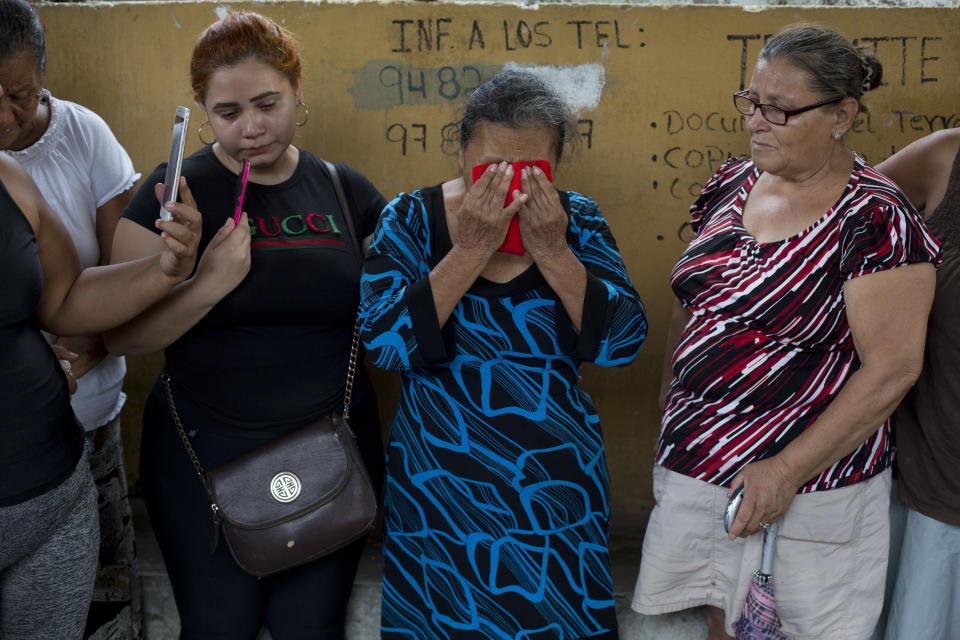 In this Oct. 31, 2018 photo, Haydee Esperanza Posadas, covers her face with a small red towel to wipe away tears and sweat, during the burial of her son Wilmer Gerardo Nunez at a cemetery in San Pedro Sula, Honduras. Eight years and three months after the last hug from her son Wilmer, Posadas says she feels peace for the first time, although she still wants justice. (AP Photo/Moises Castillo)