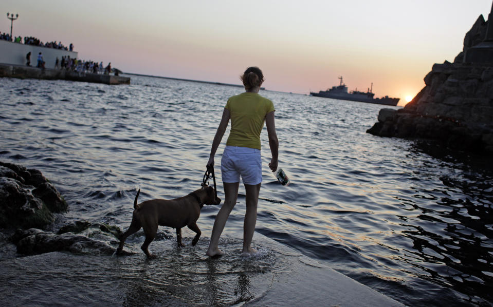 FILE - In this Saturday, July 24, 2010 file photo, a girl plays with her dog in Sevastopol, Ukraine. Despite the pebble beaches and cliff-hung castles that made Crimea famous as a Soviet resort hub, the Black Sea peninsula has long been a corruption-riddled backwater in economic terms. The Kremlin, which decided to take the region from Ukraine after its residents voted in a referendum to join Russia, has begun calculating exactly what it will cost to support Crimea’s shambolic economy _ which one Russian minister described as “no better than Palestine.” (AP Photo/Sergey Ponomarev, File)