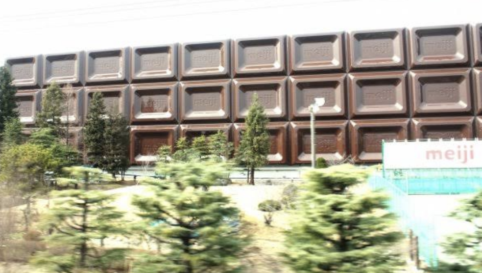Building facade resembling a bar of chocolate, with "meiji" sign in front