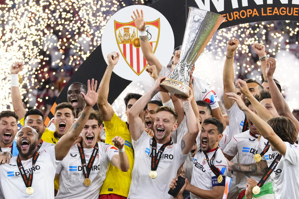 Sevilla's team captains Ivan Rakitic, center, and Jesus Navas, center right, lift the trophy after winning the Europa League final soccer match between Sevilla and Roma, at the Puskas Arena in Budapest, Hungary, Wednesday, May 31, 2023. Sevilla defeated Roma 4-1 in a penalty shootout after the match ended tied 1-1. (AP Photo/Petr David Josek)