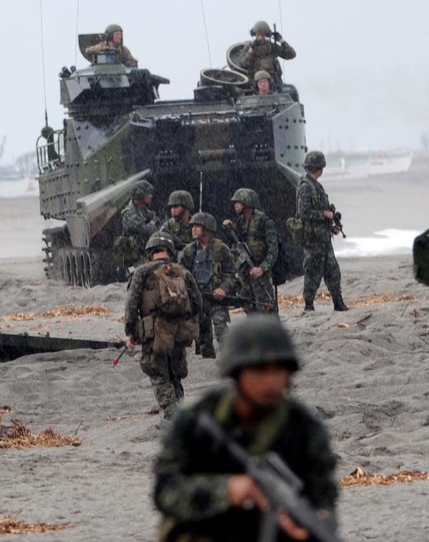 Philippine Marines take positions next to a US Marine amphibious assault vehicle (AAV) during a mock beach assault in 2014