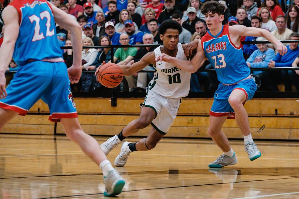 Malvern's J'Allen Barrino drives to the basket as Garaway's Brady Roden guards during the Division III District Championship Game, Friday, Mar. 3 at New Philadelphia High School.
