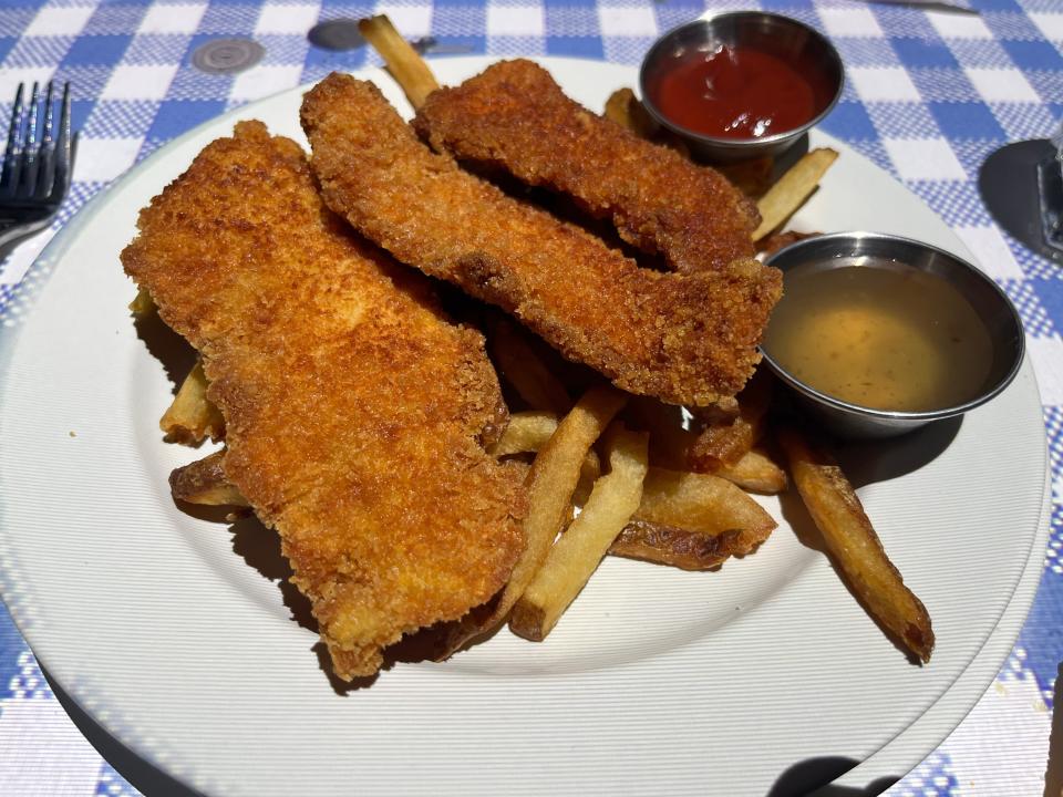White plate at Le Petit Chef with chicken fingers and fries