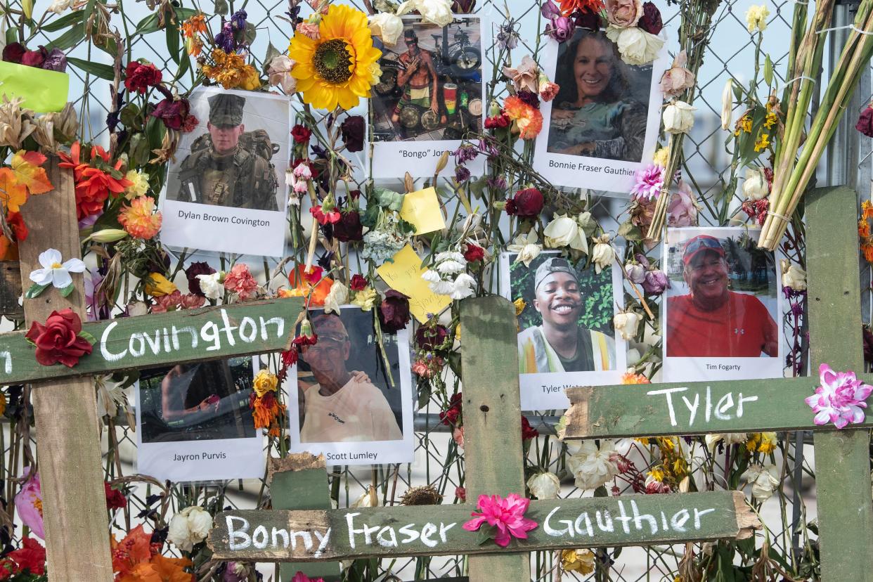 Photographs of Hurricane Ian victims cover a wall of flowers that make up a memorial at Centennial Park in Fort Myers. The memorial was started by Leo Soto, and the crosses bearing the victims' names were added by Roberto Marquez.