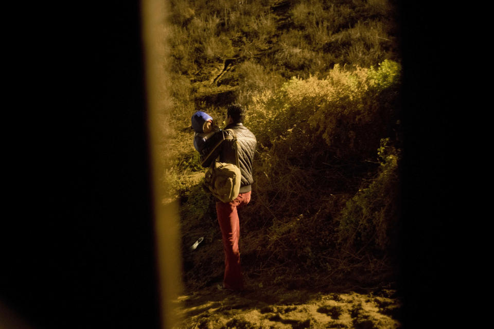 A Honduran migrant walks with his son in his arms after jumping the wall to the U.S that separates Tijuana, Mexico and San Diego, in Tijuana, Mexico, Thursday, Nov. 29, 2018. Aid workers and humanitarian organizations expressed concerns Thursday about the unsanitary conditions at the sports complex in Tijuana where more than 6,000 Central American migrants are packed into a space adequate for half that many people and where lice infestations and respiratory infections are rampant. (AP Photo/Ramon Espinosa)