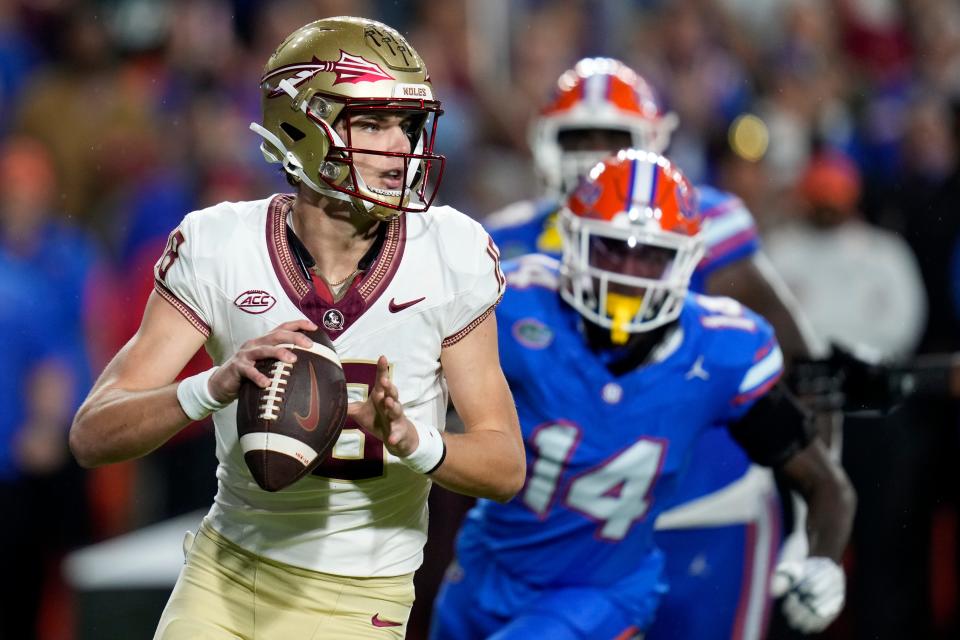 Florida State quarterback Tate Rodemaker, left, looks for a receiver as his is pressured by Florida safety Jordan Castell (14) during the first half of their game, Saturday, Nov. 25, 2023, in Gainesville, Fla.