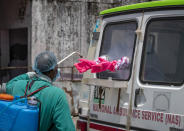 A health worker sprays disinfectant on the gloves of a doctor sitting inside a van to collect samples from people to be tested for the coronavirus in Dharmsala, India, Saturday, May 9, 2020. India relaxed some coronavirus lockdown restrictions on Monday even as the pace of infection picked up and reopenings drew crowds of people. (AP Photo/Ashwini Bhatia)