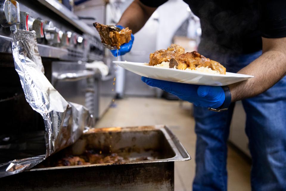 Hefdhallah Alghdry, a co-owner of Queen of Sheba, prepares a lamb haneth dish in the restaurant’s kitchen in Cordova, Tenn., on Wednesday, March 1, 2023.