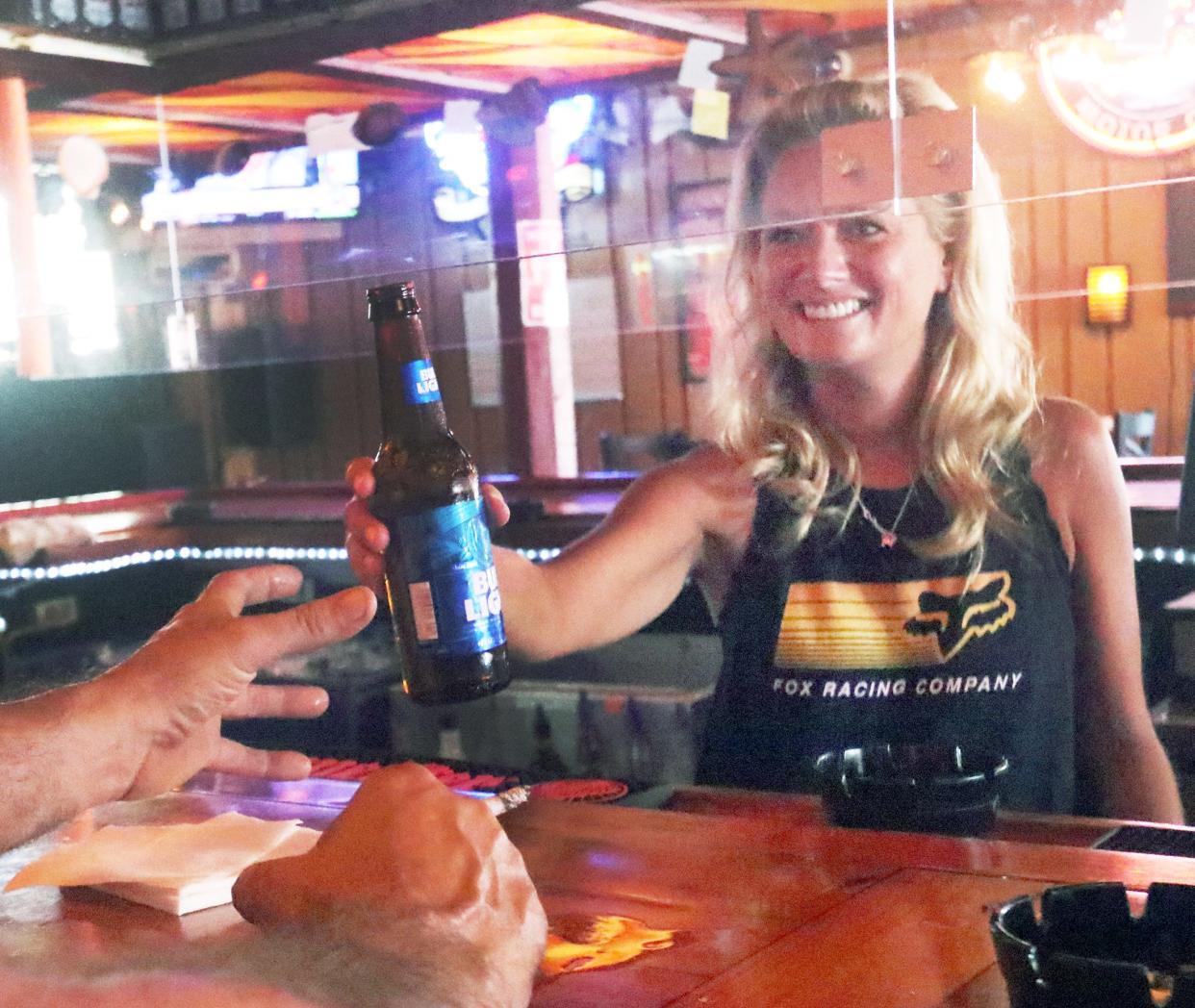 Top city leaders have been discussing a new set of stricter rules for bars throughout Daytona Beach that stay open past midnight. The rules could mandate things such as having metal detectors and scanners for customers' identification cards. Pictured is a bartender serving a customer at Dirty Harry's on Daytona Beach's Main Street in 2020.