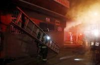 Baltimore firefighters rush ladders into position to fight fires in mutliple burning buildings set ablaze by rioters during clashes in Baltimore, Maryland April 27, 2015. REUTERS/Jim Bourg