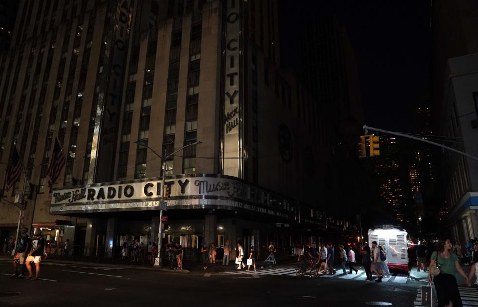 People walk past Radio City Music Hall in the dark during a major power outage affecting parts of New York City on July 13, 2019.