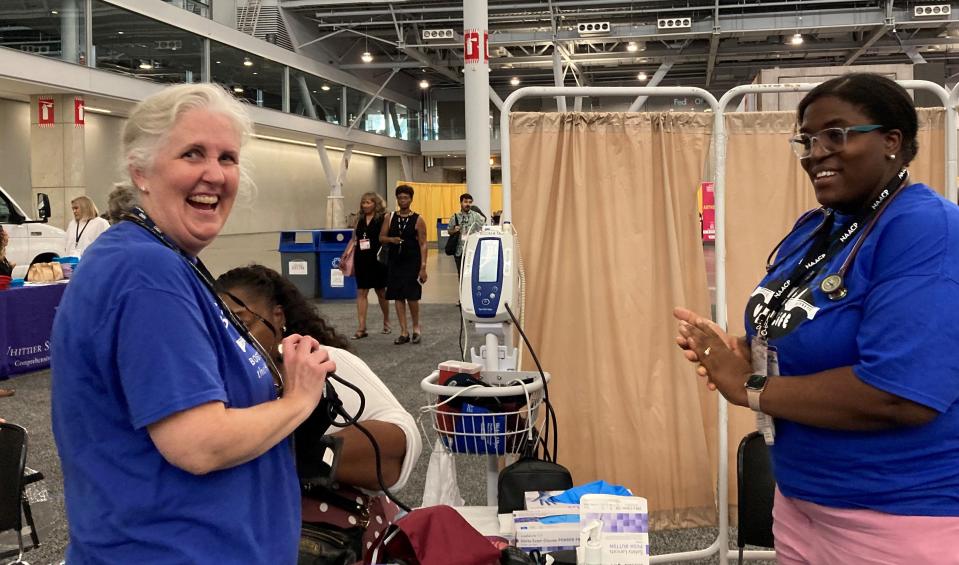 Nurse Anne Marie Murray, left, works with Dr. Paula Hercule, both with the Boston Health Care for the Homeless Program, at the NAACP national convention in Boston Friday where the organization was offering free screenings for blood pressure and blood glucose issues.