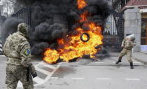 A serviceman from the Aydar battalion throws a tyre on a fire during a protest against disbanding of the battalion in front of Ukraine's Defence Ministry in Kiev, Ukraine, in this February 2, 2015 file photo. REUTERS/Valentyn Ogirenko/Files