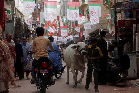 Residents walk along a street decorated with flags of political parties, ahead of general elections in the Lyari neighborhood in Karachi, Pakistan July 9, 2018. Picture taken July 9, 2018. REUTERS/Akhtar Soomro