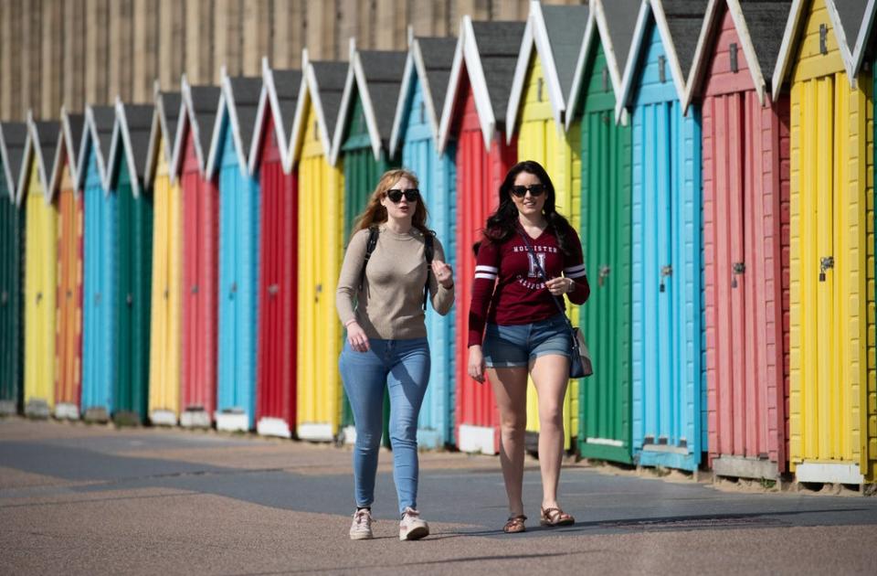 People make their way past beach huts on the sea front on Boscombe Beach in Dorset (PA Wire)