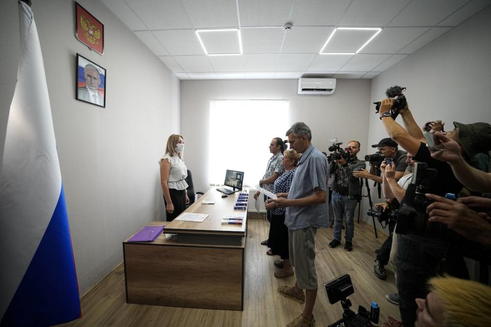 A group of Ukrainians take an oath of Russian citizenship before a portrait of Russian President Vladimir Putin in Melitopol, in southern Ukraine. This photo was taken during a trip organized by the Russian Ministry of Defense. <a href="https://newsroom.ap.org/detail/UkraineRussia/bca2dce995db48e3b846ccdea98b95ed/photo" rel="nofollow noopener" target="_blank" data-ylk="slk:AP Photo;elm:context_link;itc:0;sec:content-canvas" class="link ">AP Photo</a>