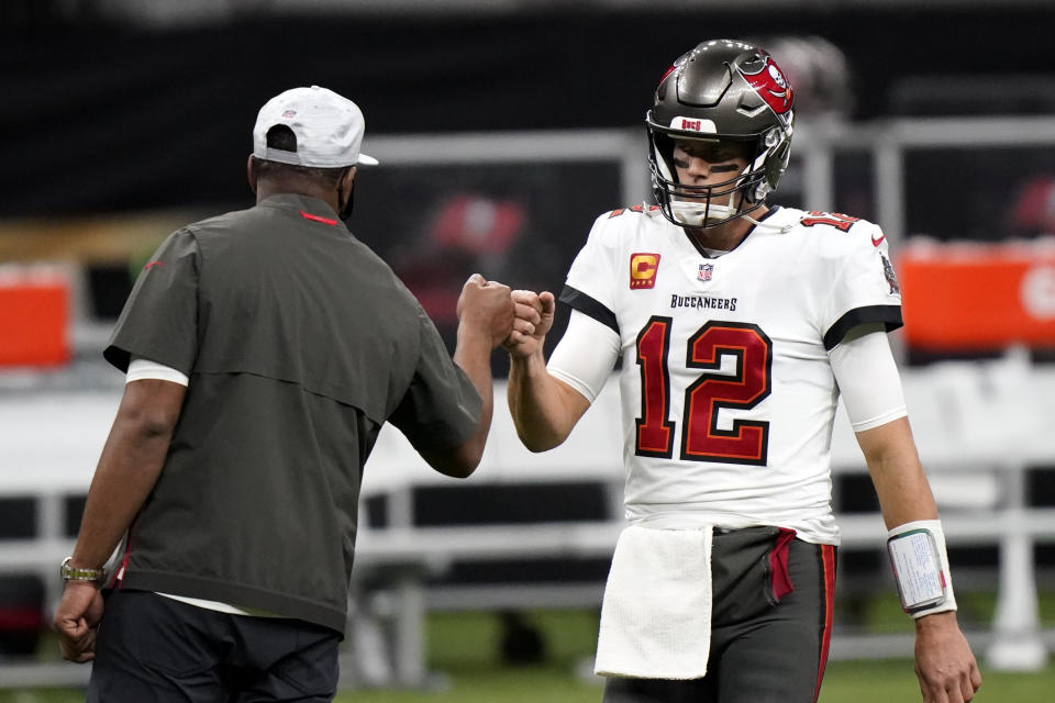 Tampa Bay Buccaneers quarterback Tom Brady (12) fist bumps with a coach before the first half of an NFL divisional round playoff football game between the New Orleans Saints and the Tampa Bay Buccaneers, Sunday, Jan. 17, 2021, in New Orleans. (AP Photo/Brynn Anderson)