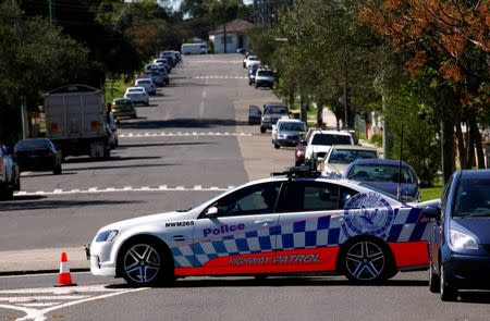 A policeman sits in his patrol car as part of a road block on the street where a house was involved in pre-dawn raids in the western Sydney suburb of Guilford September 18, 2014. REUTERS/David Gray