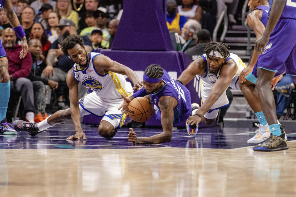 Golden State Warriors forward Andrew Wiggins and Charlotte Hornets forward Jalen McDaniels dive for a loose ball during the first half of an NBA basketball game on Saturday, Oct. 29, 2022, in Charlotte, N.C. (AP Photo/Scott Kinser)