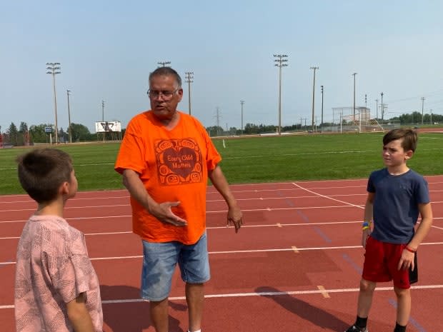 Coach Terry Crook doles out advice to fledgling track athletes Hadine and Dakin Robinson. The endurance coach with the Calgary Spartans Track and Field Club has been nominated for a prestigious National Indigenous Coaching Award. (Carolyn Dunn/CBC - image credit)