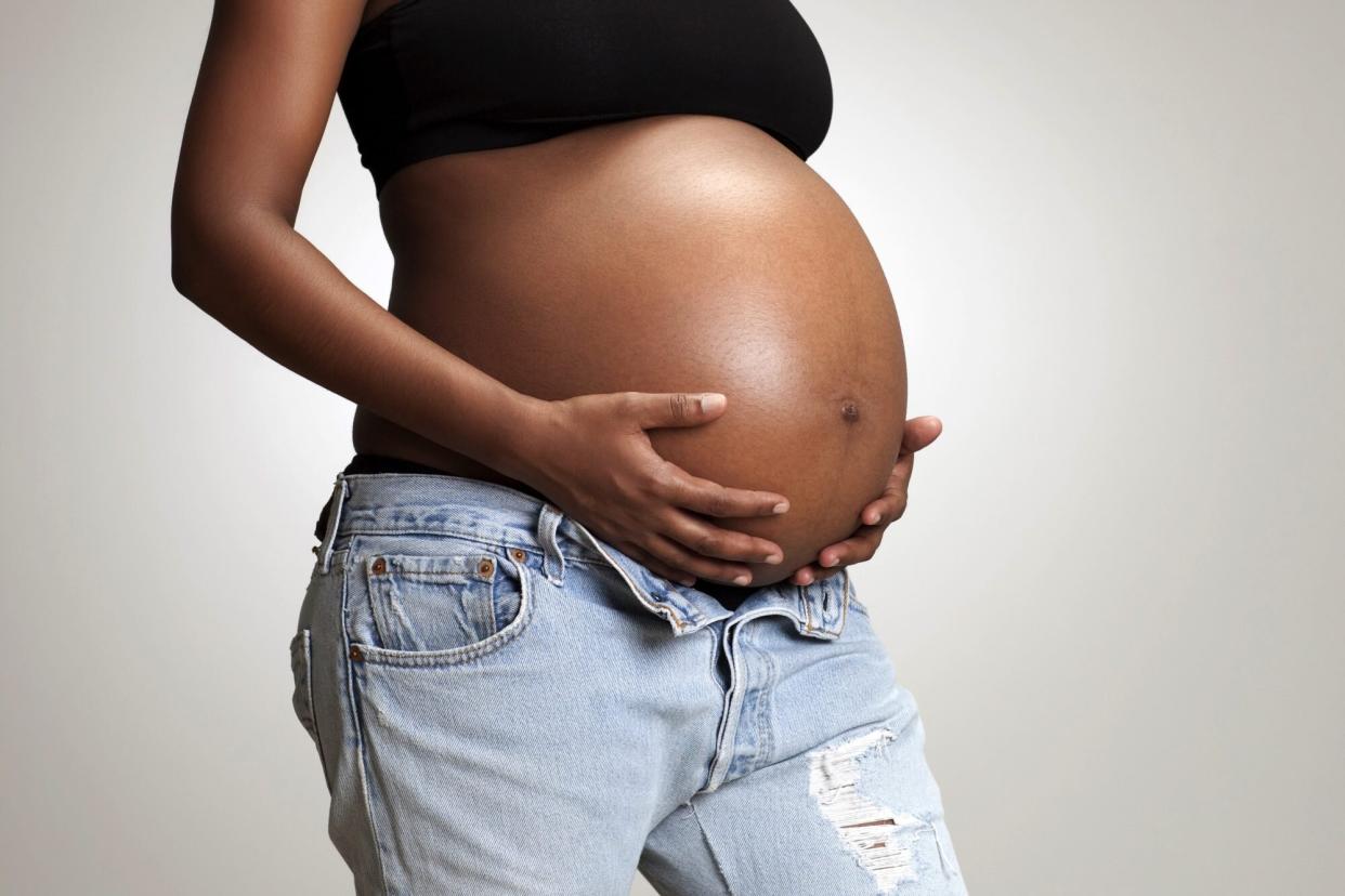 Black woman holding her pregnant belly