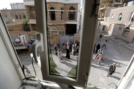 People are pictured through a damaged window of a house near the site of a car bomb attack in Sanaa June 30, 2015. A car bomb claimed by Islamic State exploded in the Yemeni capital Sanaa overnight, medics said, wounding at least 28 people gathered to mourn another attack earlier this month. REUTERS/Khaled Abdullah