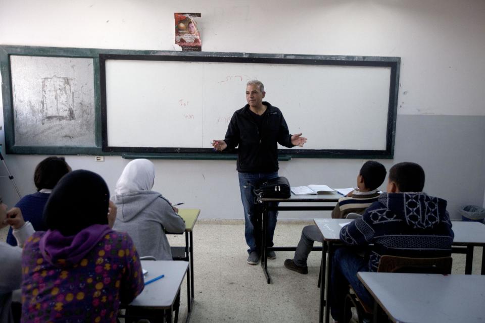 In this Thursday, April 3, 2014 photo, Palestinian Esmat Mansour, a former prisoner who was released after 20 years in Israeli jail, teaches Hebrew to students at a school in the village of Taybeh, near the West Bank city of Ramallah. Mansour was 16 when, in October 1993, he helped three older teens stab to death an Israeli man. Mansour said the time in Israeli prison changed him. (AP Photo/Majdi Mohammed)