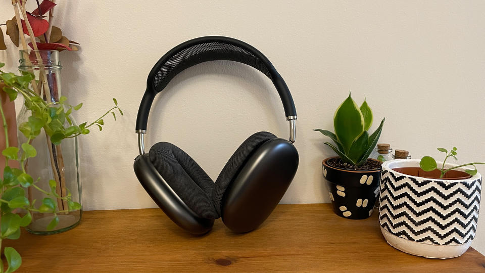 Grey AirPods Max on a wooden desk next to plants