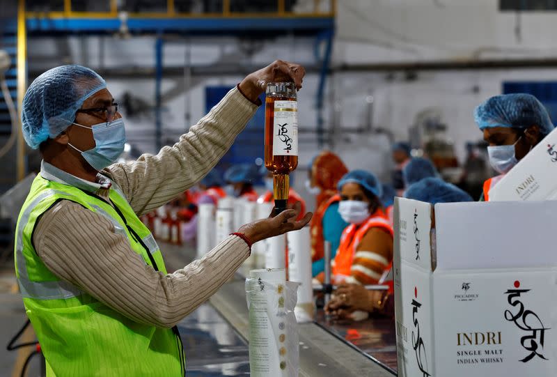 A worker inspects a whisky bottle before packaging inside Piccadily Distilleries in Indri