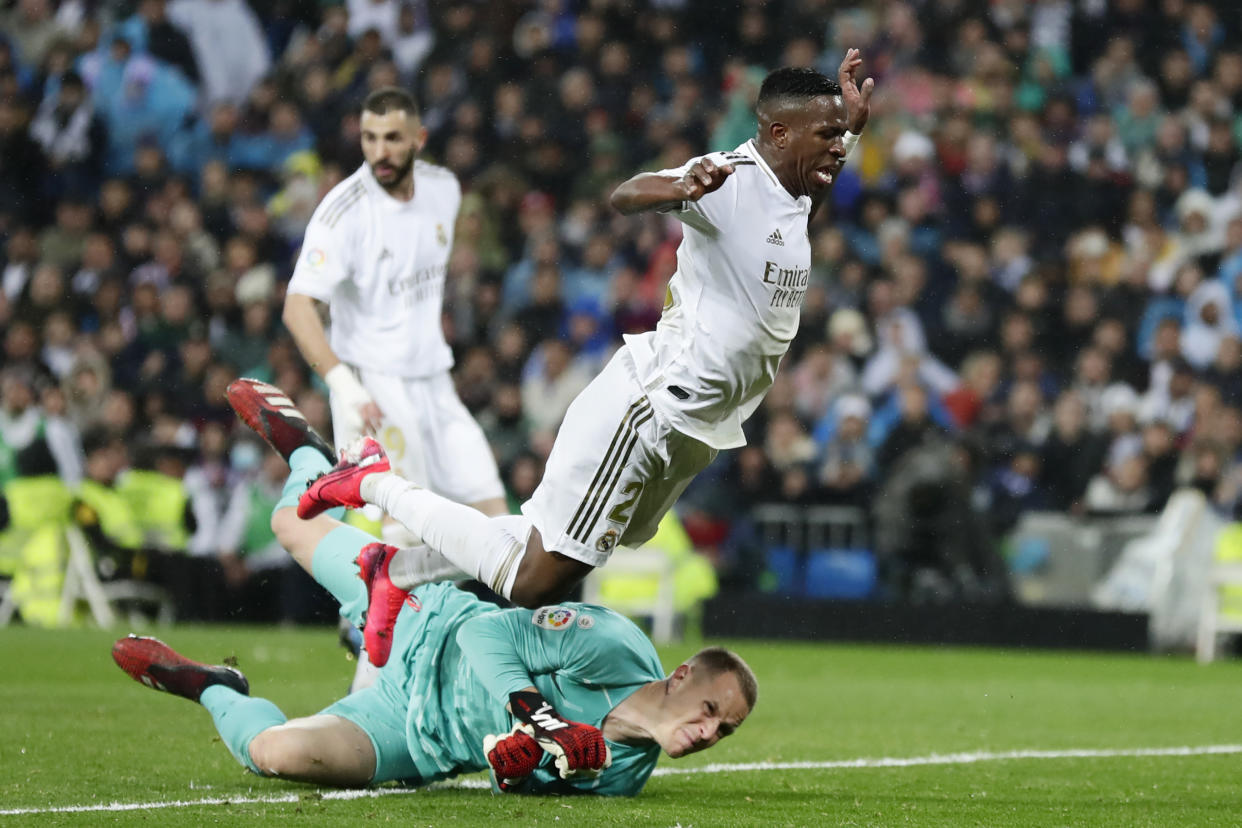 Real Madrid's Vinicius Junior, right, and Barcelona's goalkeeper Marc-Andre ter Stegen, bottom, compete for the ball during the Spanish La Liga soccer match between Real Madrid and Barcelona at the Santiago Bernabeu stadium in Madrid, Spain, Sunday, March 1, 2020. (AP Photo/Manu Fernandez)