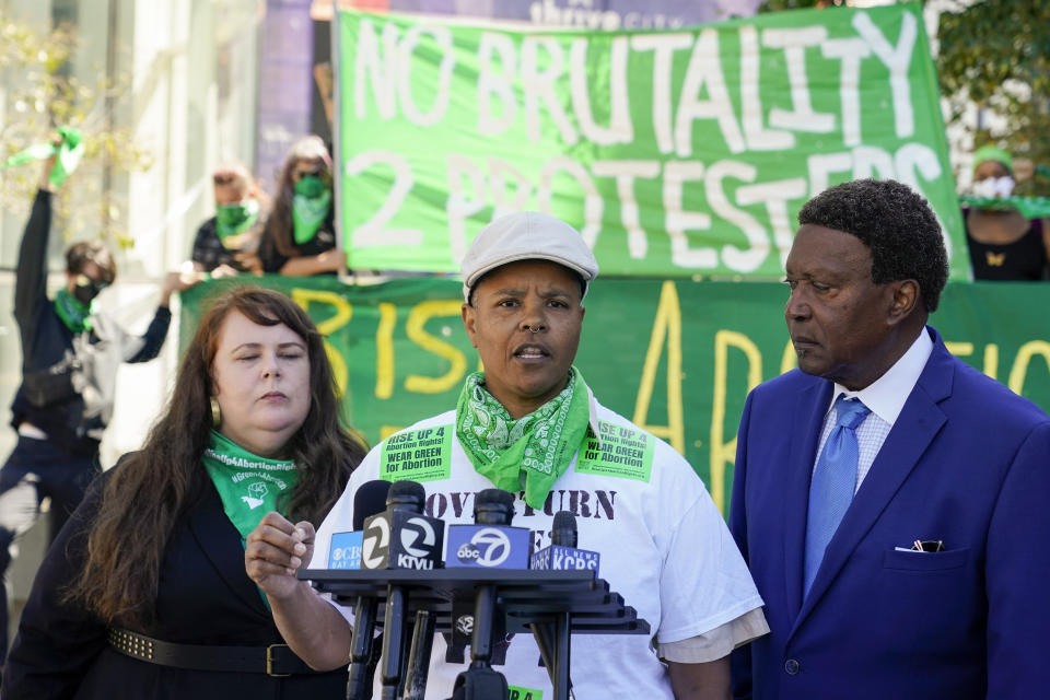 Kareim McKnight, center, talks to reporters during a press conference outside Chase Center, announcing the filing of a federal civil rights lawsuit against the San Francisco Fire and Police Departments in San Francisco, Wednesday, Aug. 10, 2022. McKnight alleges a paramedic, under the orders of a police sergeant, injected her with a sedative while she was handcuffed after protesting the Supreme Court's Roe v. Wade decision during a Golden State Warriors championship game. (AP Photo/Godofredo A. Vásquez)