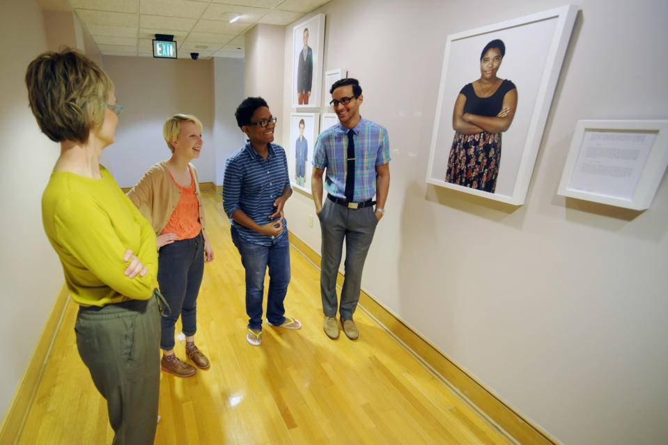 In this photo taken on Monday, April 21, 2014, photographer Carolyn Sherer, left, looks at her new exhibit featuring images of young people with varied sexual identities and preferences during the installation work in Birmingham, Ala. From second left, Foster Noone, 17; Lauren Jacobs, 22; and Ali Massoud, 20, are among a dozen young people who posed for the photos in the exhibit, which opens Wednesday, April 23, at the Birmingham Civil Rights Institute. (AP Photo/Jay Reeves)