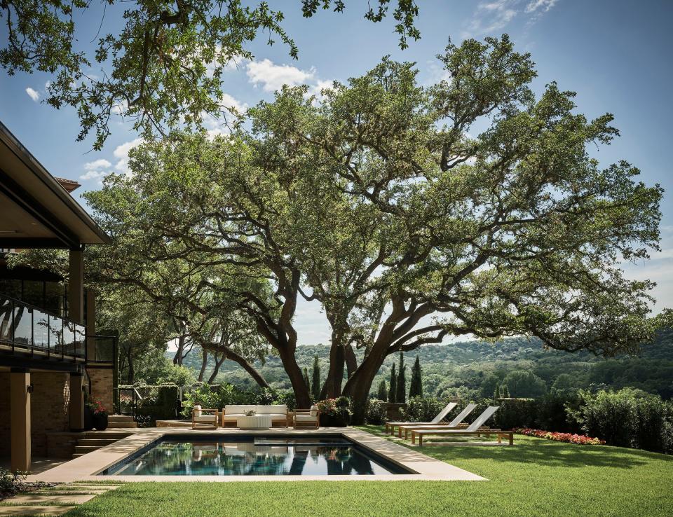 A massive oak tree adds beauty and shade to the garden, which is perched on Lake Austin. The loungers are from RH, and the teak sofa and armchairs are from Harbour Outdoor. Architect Ryan Street added a pool during the reconstruction of the home.