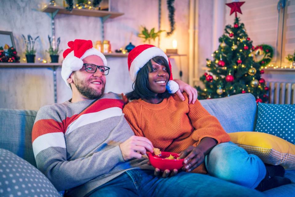 young couple watching holiday movies on couch