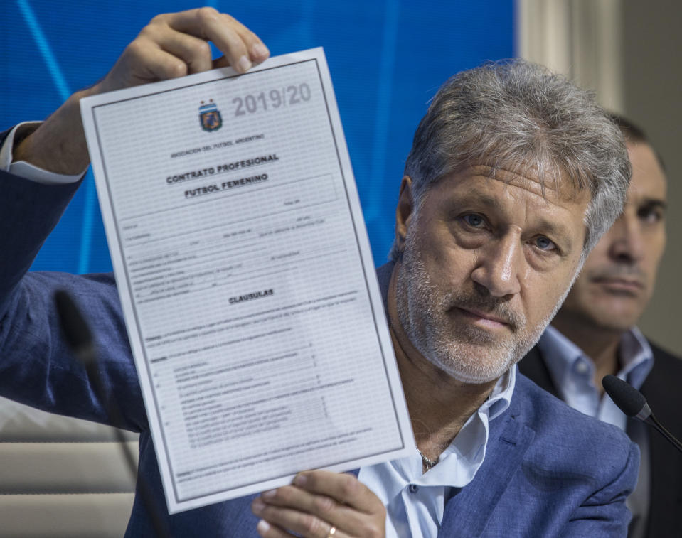 General Secretary of the Argentina's Footballers' Union (FAA) Sergio Marchi holds up the contract to implement a plan to professionalize women's soccer during a preseason conference in Buenos Aires, Argentina, Saturday, March 16, 2019. Almost 90 years after men's soccer turned professional in Argentina, the women's game is still being played by amateur athletes who get little to no money for their work on the field. (AP Photo/Daniel Jayo)