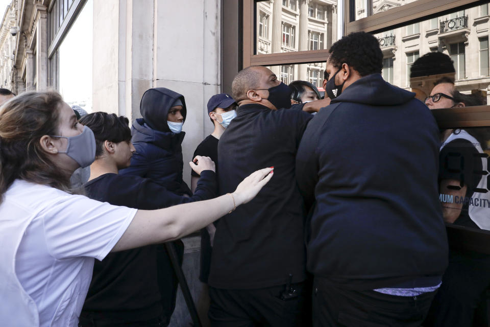 People push to enter the Niketown shop in London, Monday, June 15, 2020. After three months of being closed under coronavirus restrictions, shops selling fashion, toys and other non-essential goods are being allowed to reopen across England for the first time since the country went into lockdown in March.(AP Photo/Matt Dunham)