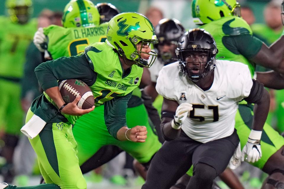 South Florida quarterback Byrum Brown (17) runs past UCF defensive end Malachi Lawrence (51) during the first half of an NCAA college football game Saturday, Nov. 26, 2022, in Tampa, Fla. (AP Photo/Chris O'Meara)