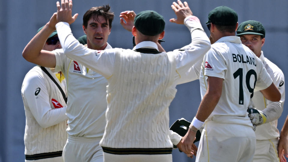 Pat Cummins celebrates a wicket with Australian teammates.